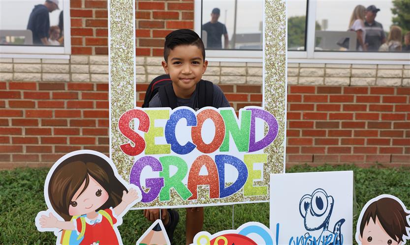 A student takes a photo with a back-to-school sign